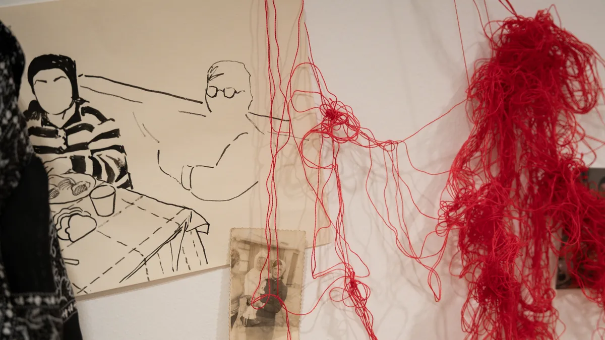 Tangled red wool thread descending beside the family table drawing and vintage photograph